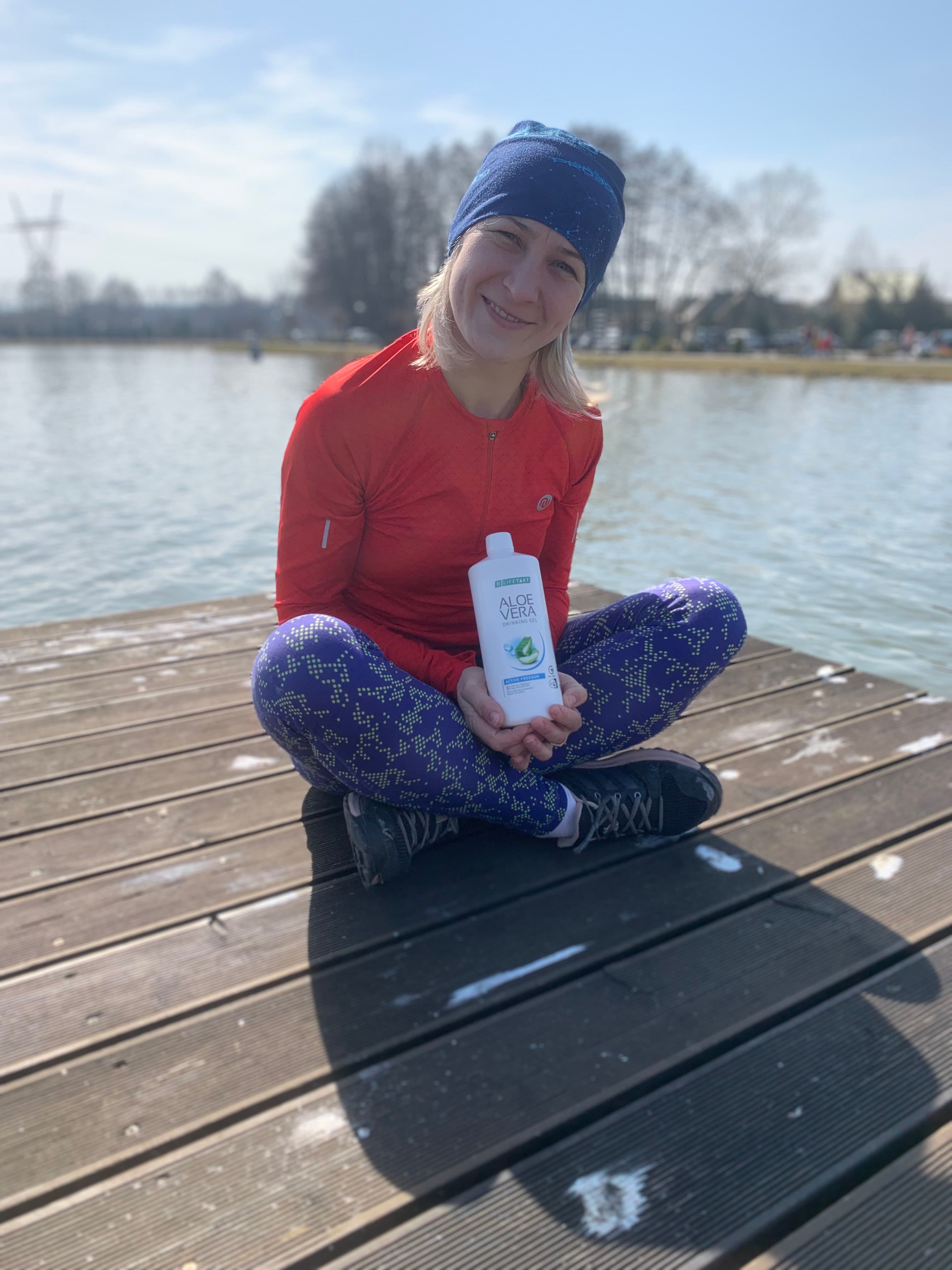 Aleksandra Kost z produktem aloesowym LR nad jeziorem